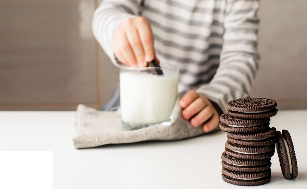 Oreo and kid's hands with cookies and milk