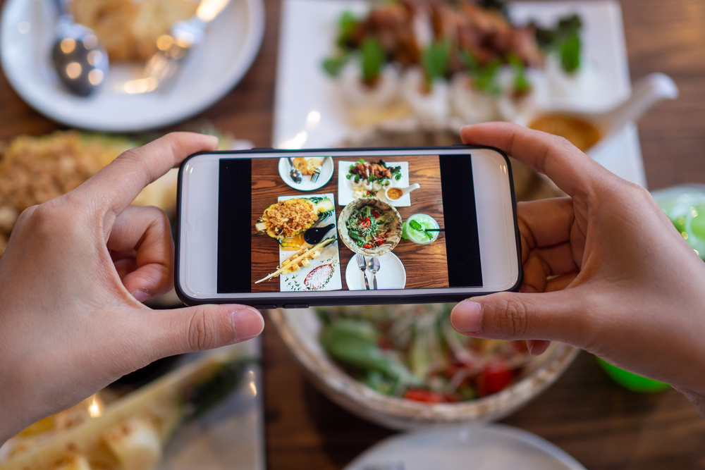 Woman taking picture of food with phone for social media