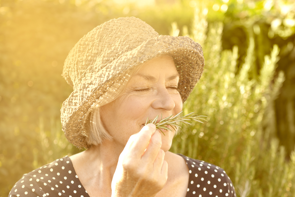 Elderly woman enjoys familiar aroma of rosemary
