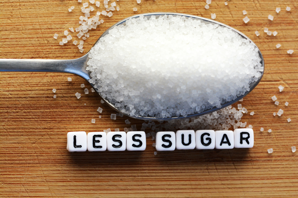 Reducing sugar -Less sugar text from tiled letter blocks and sugar pile on a spoon