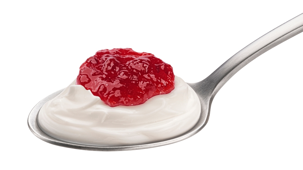 Flavor synergy - a spoon with thick yogurt and strawberry jam